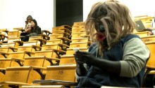 Dzunukwa in Class : photo de Cole Speck montrant un homme dans une salle de cours portant un masque sculpté par Beau Dick.